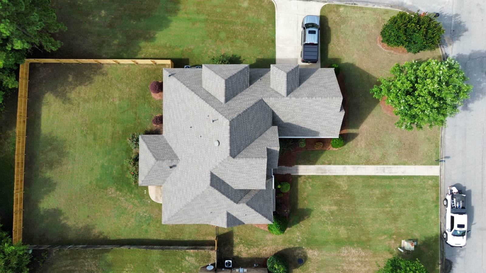 Top-down drone view of a completed multi-gable shingle roof replacement in Alabama