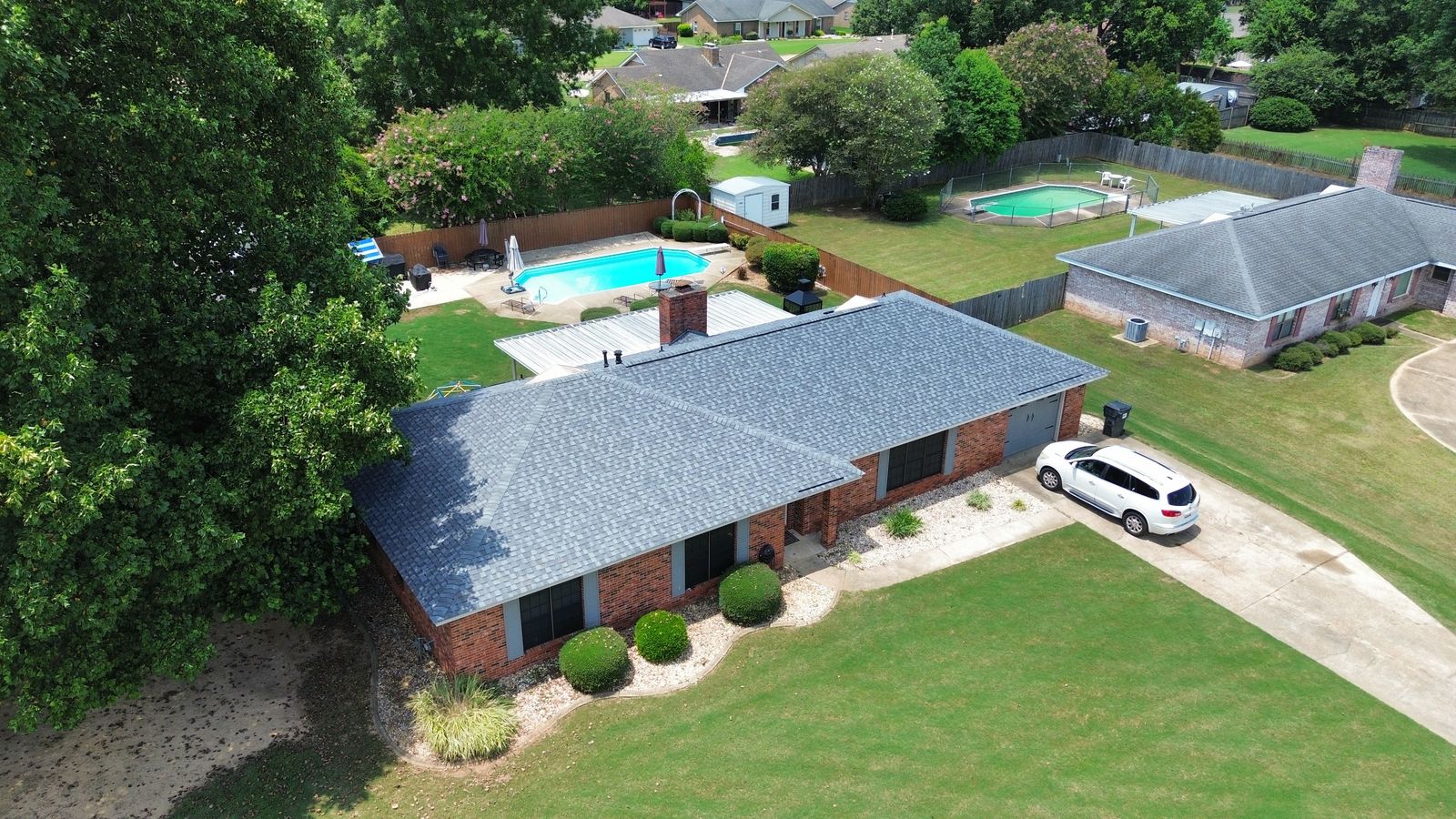 Aerial view of a new roof on an Alabama brick home with backyard pool