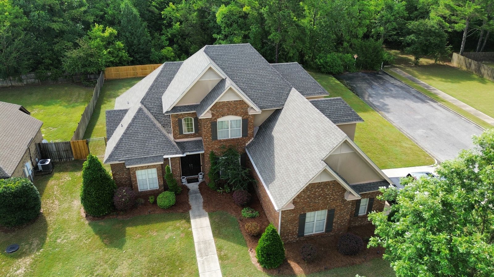 Drone view of a completed architectural shingle roof replacement on a two-story brick Alabama home by Precision Roofing Alabama