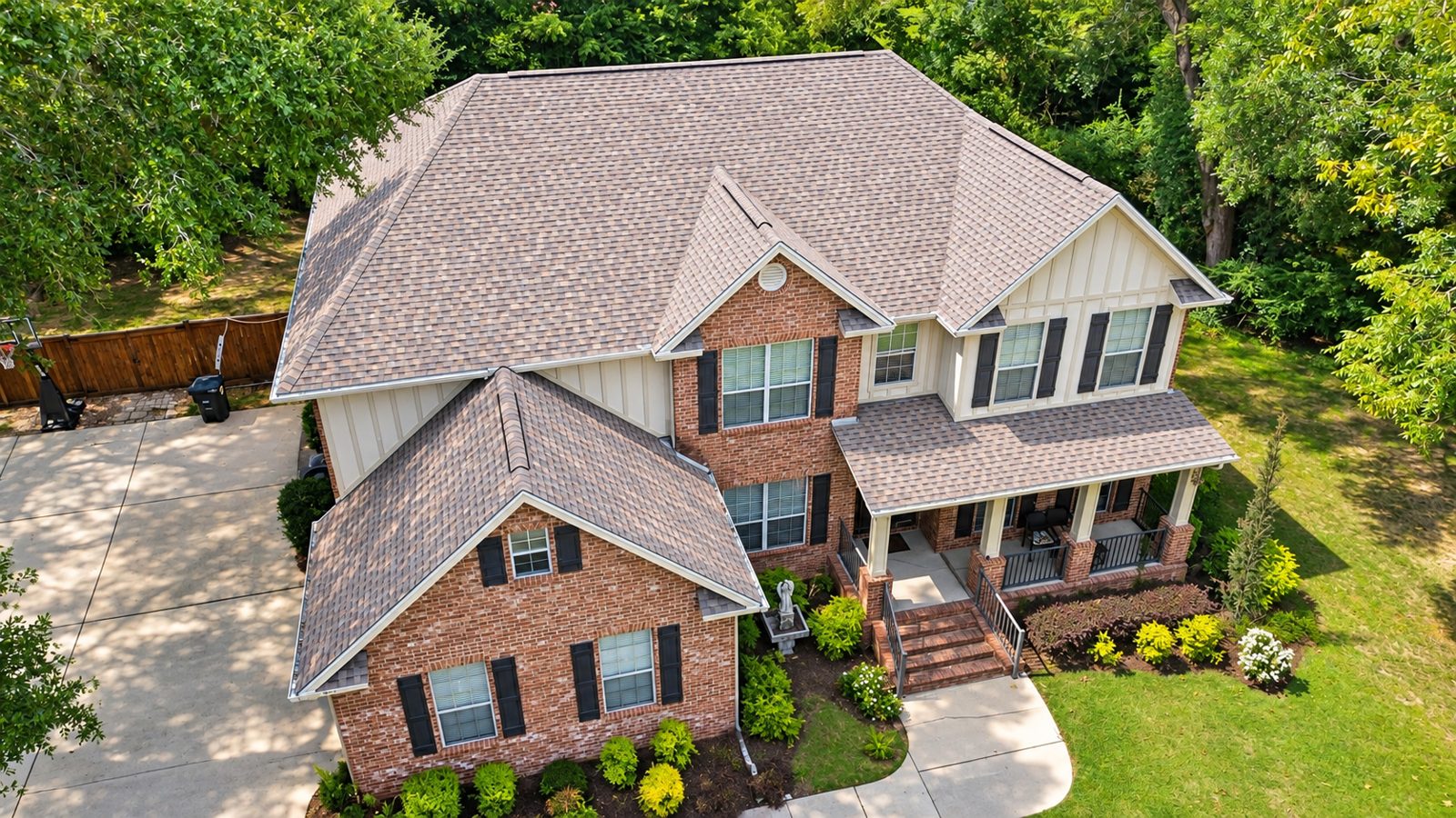 Drone view of a completed FORTIFIED certified roof replacement in Fairhope, Alabama with TAMKO Titan XT shingles in Desert Sand on a two-story brick and board-and-batten home
